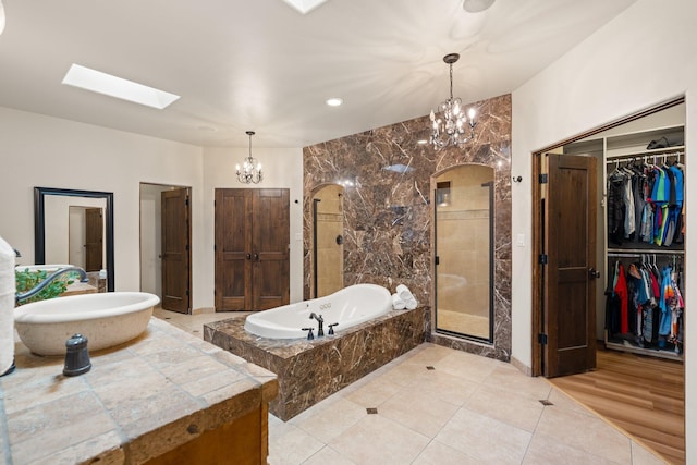 full bathroom with a sink, a bath, a stall shower, a walk in closet, and an inviting chandelier