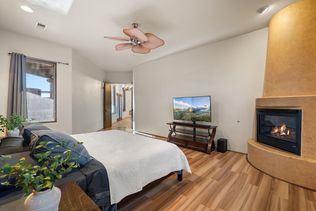 bedroom with recessed lighting, visible vents, a glass covered fireplace, ceiling fan, and wood finished floors