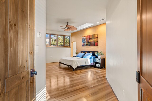 bedroom featuring light hardwood / wood-style floors, a closet, ceiling fan, and a walk in closet