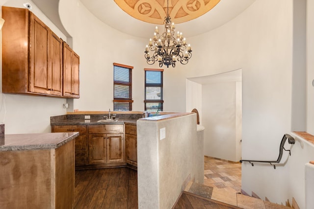 kitchen featuring dark countertops, a raised ceiling, brown cabinets, and hanging light fixtures