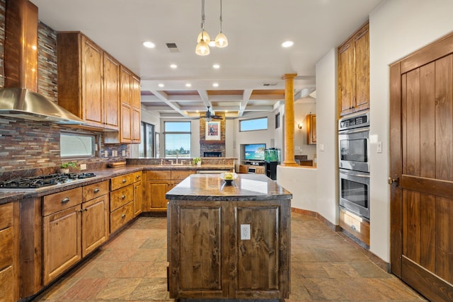 kitchen with stainless steel appliances, a peninsula, coffered ceiling, a center island, and wall chimney exhaust hood