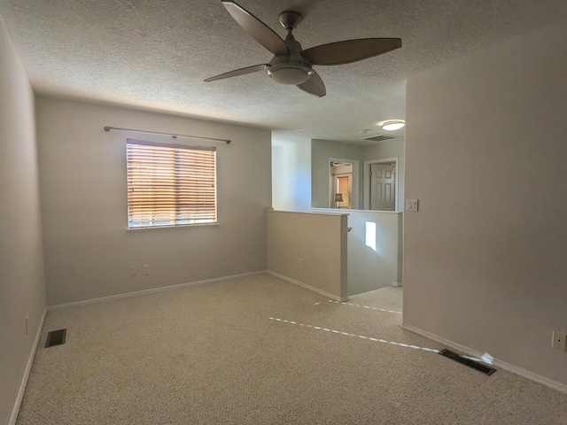 empty room with a textured ceiling, light colored carpet, and ceiling fan