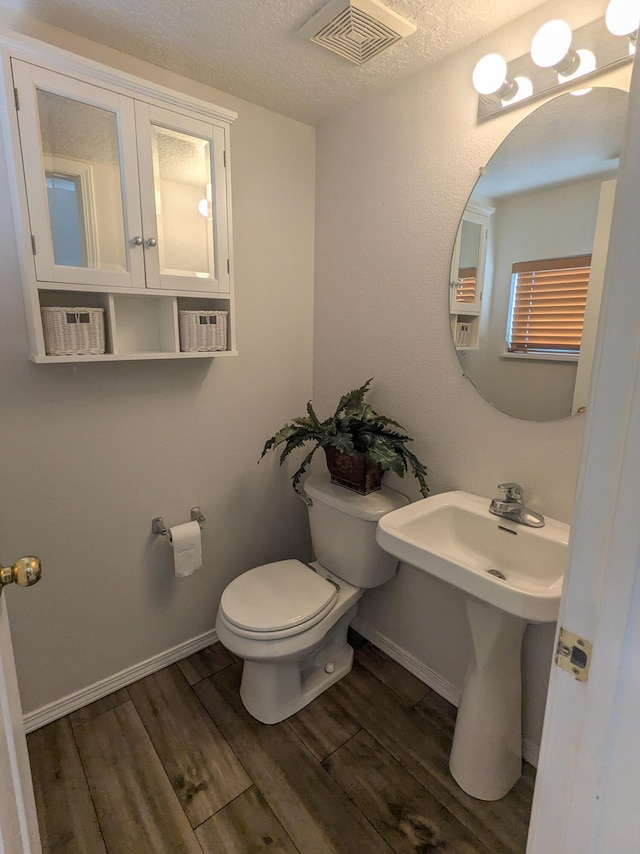 bathroom featuring a textured ceiling, wood-type flooring, and toilet