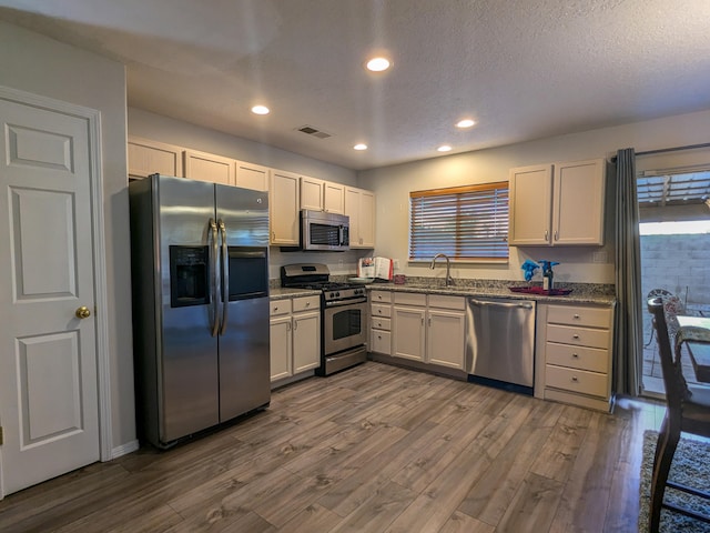 kitchen featuring dark stone counters, dark hardwood / wood-style flooring, stainless steel appliances, and plenty of natural light