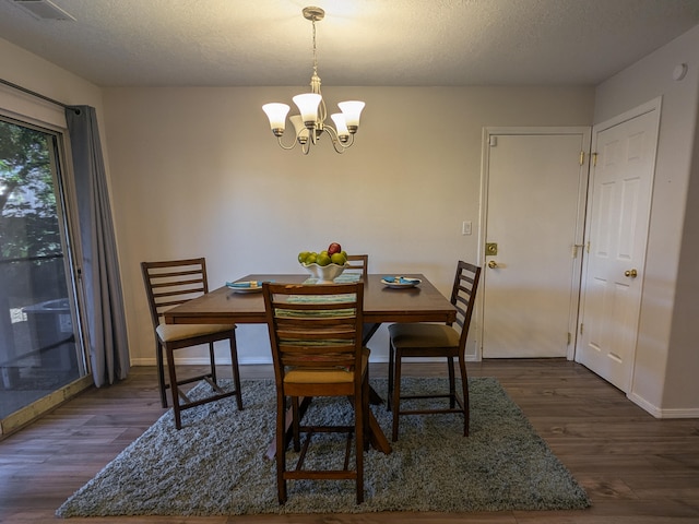 dining space featuring a textured ceiling, dark hardwood / wood-style floors, and a chandelier