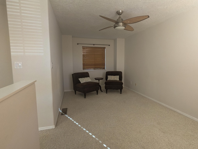 living area with a textured ceiling, ceiling fan, and light carpet