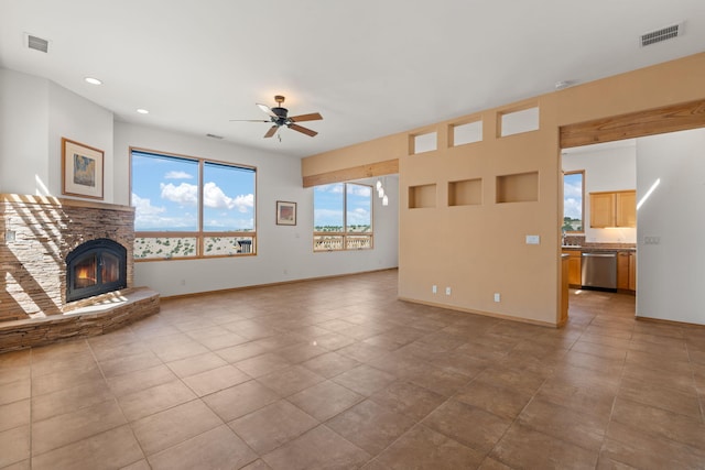 unfurnished living room featuring light tile patterned floors, a stone fireplace, and ceiling fan