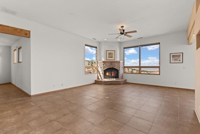 unfurnished living room featuring a fireplace, light tile patterned flooring, and ceiling fan