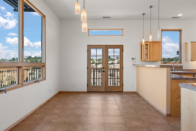 kitchen with hanging light fixtures, light tile patterned floors, sink, french doors, and light brown cabinetry