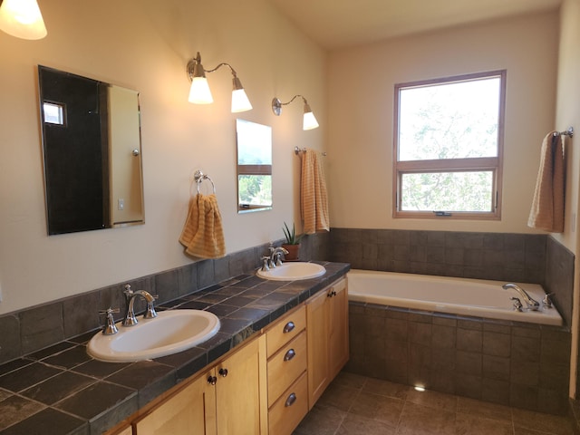 bathroom with tile patterned flooring, tiled bath, and vanity