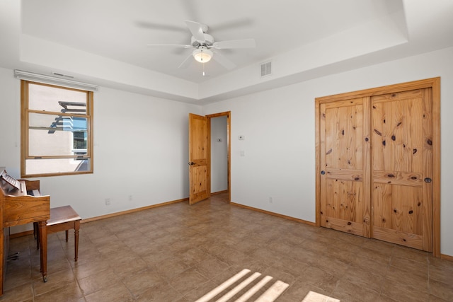 unfurnished bedroom with a tray ceiling and ceiling fan