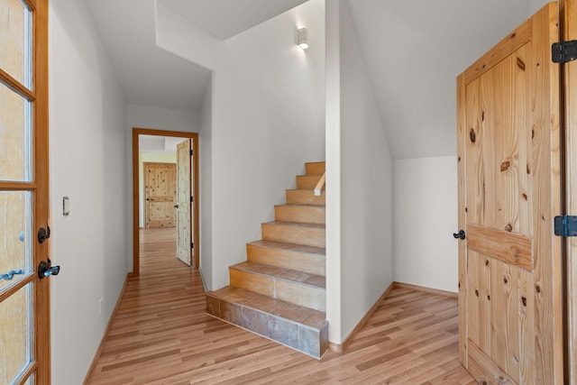 stairway with wood-type flooring and vaulted ceiling