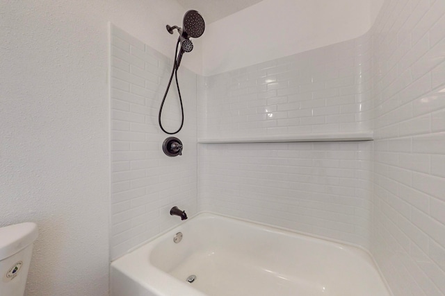 bathroom featuring toilet and tiled shower / bath