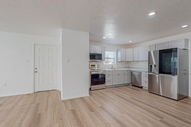 kitchen with sink, appliances with stainless steel finishes, and light hardwood / wood-style floors