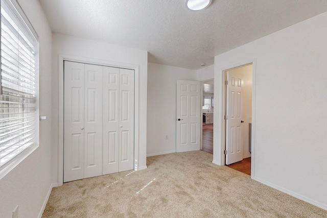 unfurnished bedroom featuring a closet, light colored carpet, and a textured ceiling