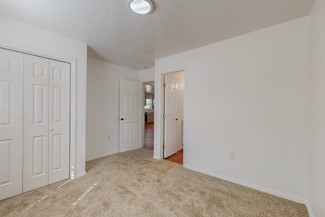 unfurnished bedroom featuring a textured ceiling, light carpet, and a closet