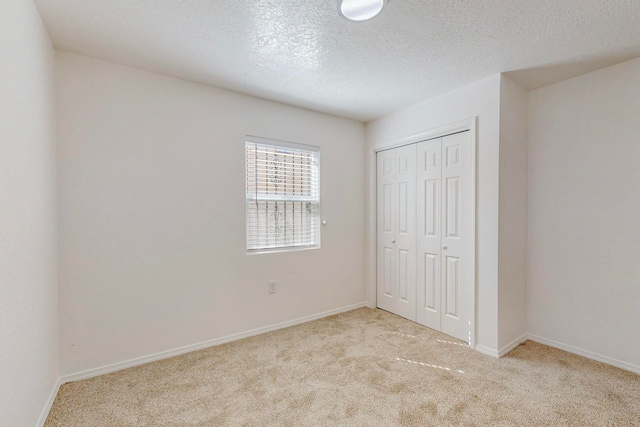 unfurnished bedroom featuring a textured ceiling, light colored carpet, and a closet