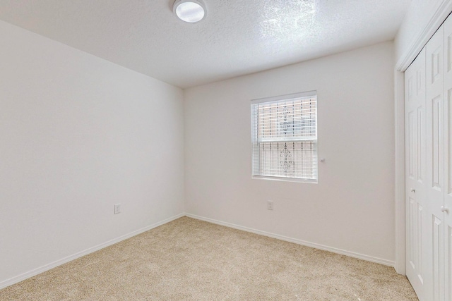 unfurnished bedroom with a closet, light colored carpet, and a textured ceiling