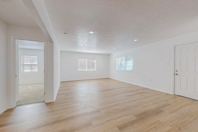 unfurnished room with a textured ceiling, light hardwood / wood-style flooring, and plenty of natural light