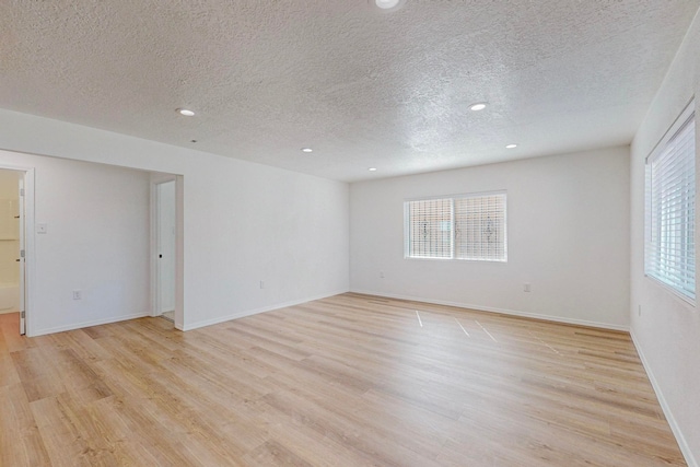 empty room with light hardwood / wood-style flooring and a textured ceiling