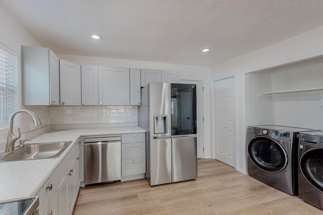 kitchen featuring light hardwood / wood-style floors, sink, white cabinetry, stainless steel appliances, and separate washer and dryer