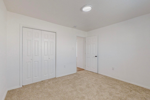 unfurnished bedroom featuring a closet and light colored carpet