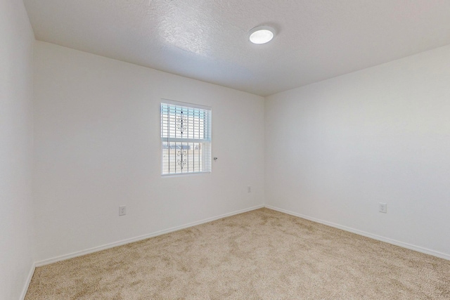 empty room with light colored carpet and a textured ceiling