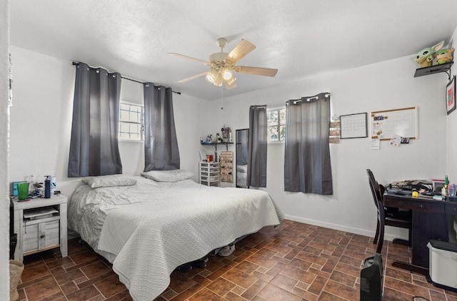 bedroom with ceiling fan, multiple windows, and a textured ceiling