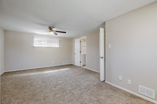 empty room featuring a textured ceiling, carpet flooring, visible vents, and a ceiling fan