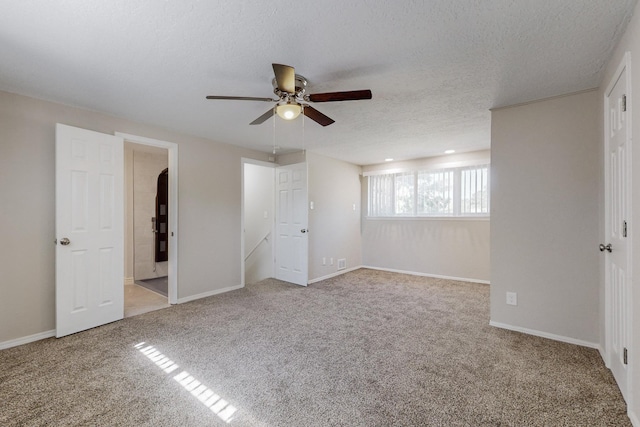 unfurnished bedroom with a ceiling fan, carpet, a textured ceiling, and baseboards