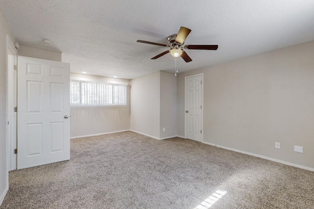 carpeted empty room featuring a textured ceiling, ceiling fan, and baseboards