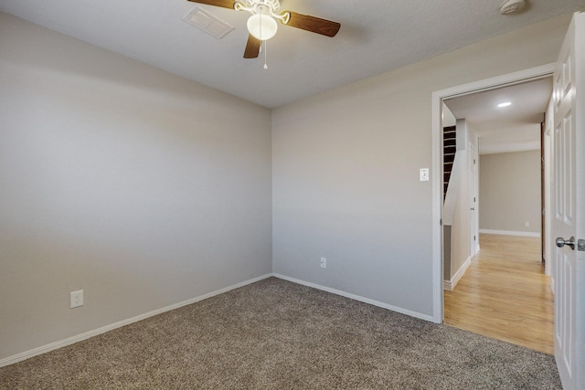 unfurnished room featuring baseboards, visible vents, a ceiling fan, and light colored carpet