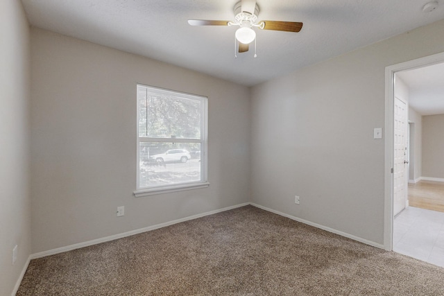 unfurnished room featuring a ceiling fan, light colored carpet, and baseboards