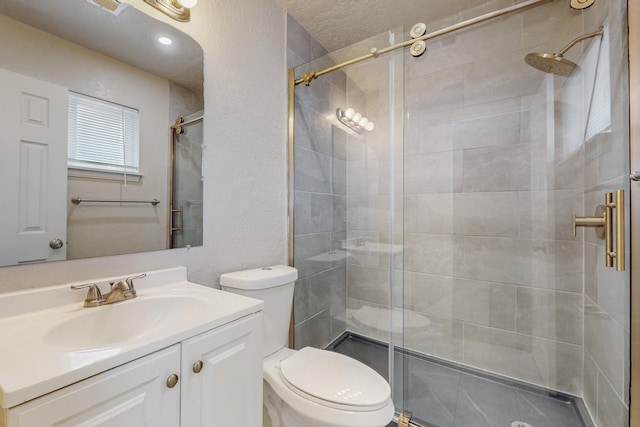 bathroom featuring a textured wall, a stall shower, vanity, and toilet