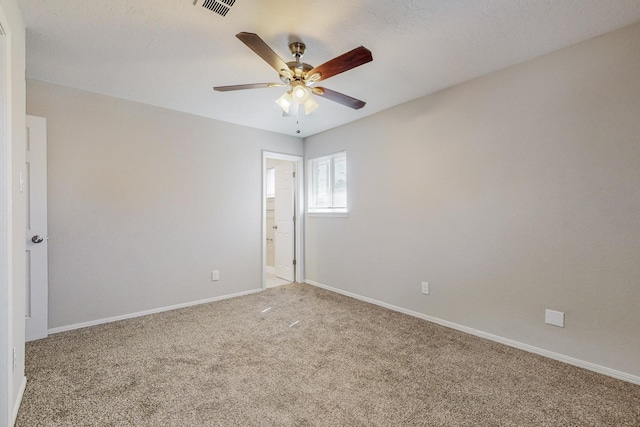 carpeted empty room featuring visible vents, a ceiling fan, and baseboards