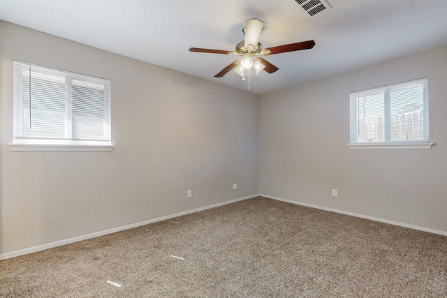 carpeted empty room with baseboards, a ceiling fan, visible vents, and a healthy amount of sunlight