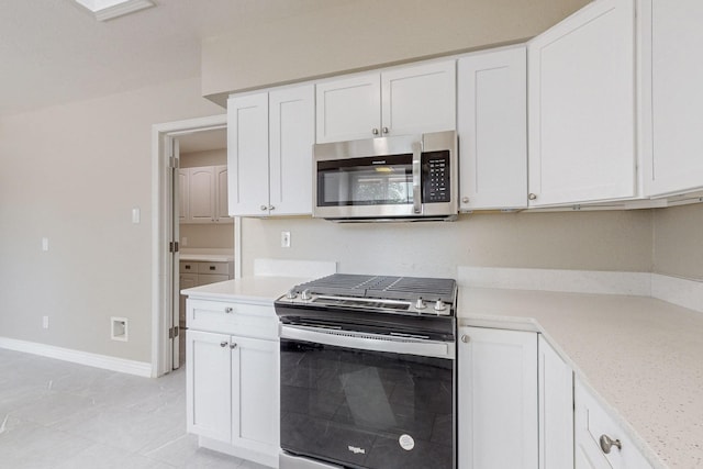 kitchen with stainless steel appliances, white cabinets, light countertops, and baseboards