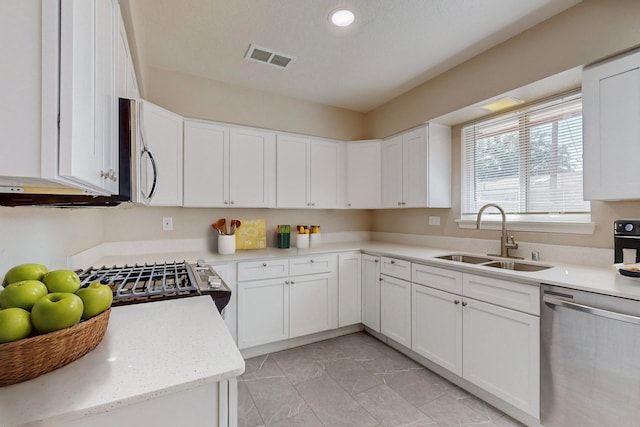 kitchen with white cabinets, stainless steel appliances, sink, and light stone countertops