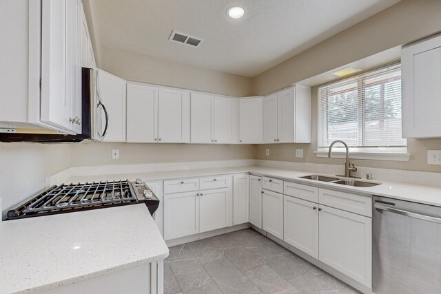 kitchen featuring stainless steel appliances, ceiling fan, a skylight, and white cabinetry