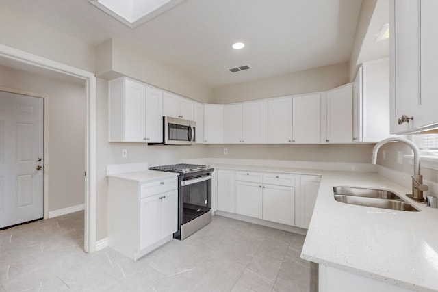 kitchen with a skylight, a sink, visible vents, white cabinets, and appliances with stainless steel finishes