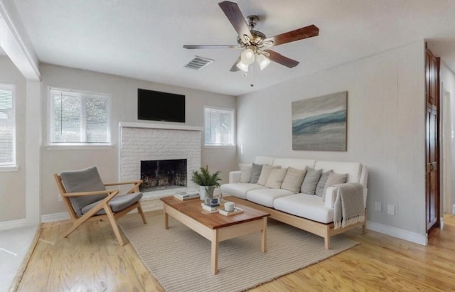 living area with light wood finished floors, baseboards, visible vents, a ceiling fan, and a fireplace