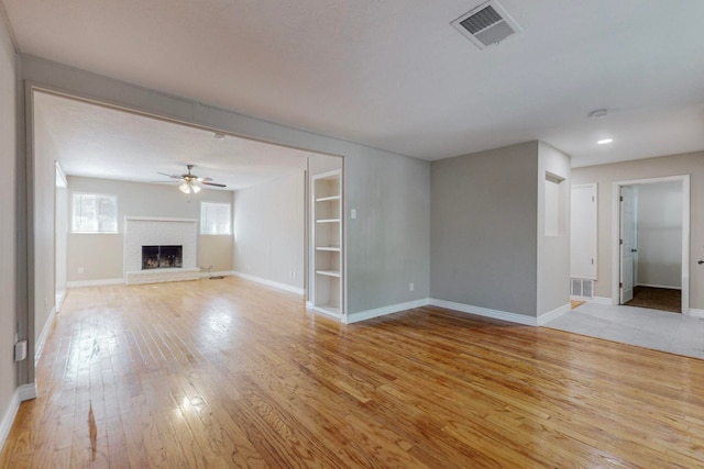 unfurnished living room featuring a fireplace, light wood-type flooring, and ceiling fan