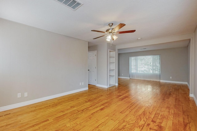 unfurnished room featuring built in features, baseboards, visible vents, a ceiling fan, and light wood-style flooring