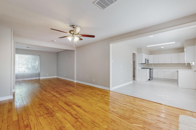 unfurnished living room with ceiling fan, light wood-type flooring, and sink