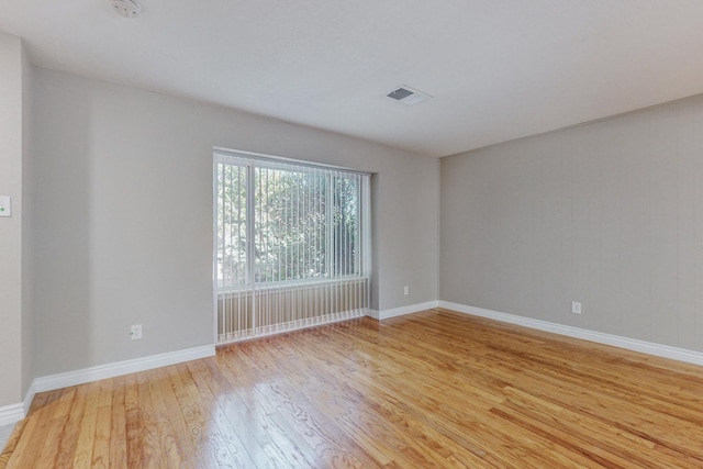 empty room featuring baseboards, visible vents, and light wood-style floors