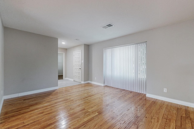 unfurnished room featuring light wood finished floors, visible vents, and baseboards