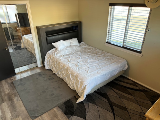 bedroom featuring wood-type flooring, a closet, and multiple windows