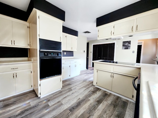 kitchen featuring black oven, electric stovetop, white cabinetry, and light hardwood / wood-style flooring