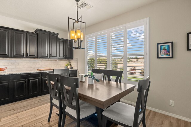 dining area with light hardwood / wood-style floors and a notable chandelier