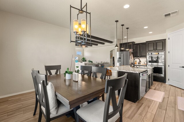 dining area featuring light wood-type flooring, sink, and an inviting chandelier